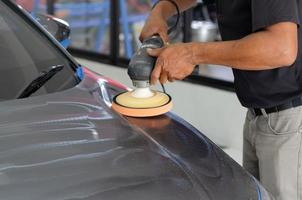 detalle del coche - mecánico masculino que sostiene la máquina pulidora del coche. industria automotriz, taller de pulido y pintura y reparación de automóviles. foto