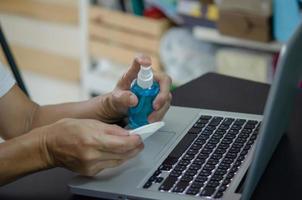 Spraying alcohol to clean the computer and wipe the germs. Health care concept. photo