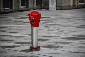 Red hydrant standing on city gray tiled square photo