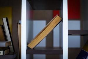 Book standing in diagonal on shelf on dark blurred background photo
