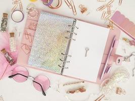 Diary open with white and holographic page. Pink planner with cute stationery. Top view of the pink planner with stationery. Pink glamour planner decoration photo