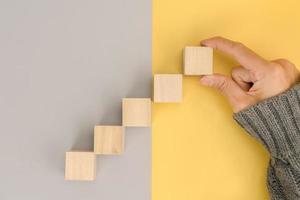 Woman hand arranging empty wood block and copy space on grey and yellow background photo