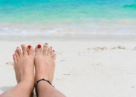 Woman feet and red nails on the beach photo