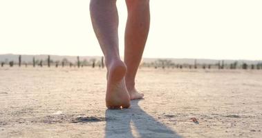Close up of male barefoot legs walk in the hot summer desert, global warming concept video