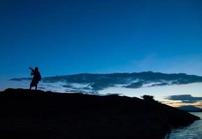 Silueta de fotógrafo tomando fotografías del paisaje durante el amanecer foto