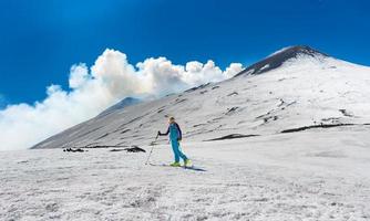 Girl ski touring under the top of the crater of Mount Etna photo