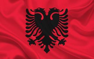 Bandera del país de Albania sobre un fondo de tela de seda ondulada foto