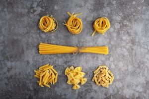 Five types of different pasta lie on a gray table photo