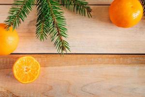 Frame made of fir branches and tangerines on wooden background. Christmas decor. photo