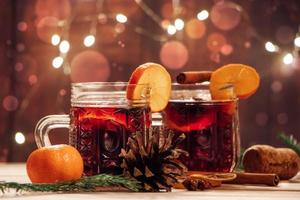 Hot mulled wine with fruits and spices on wooden background. Winter warming holiday drink. photo