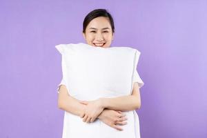 Asian woman holding upper pillow, isolated on purple background photo