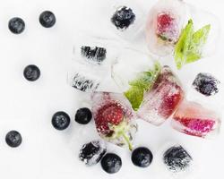 Berries in ice on white surface photo