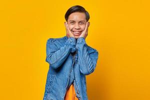 Portrait of surprised young Asian man looking at camera isolated on yellow background photo