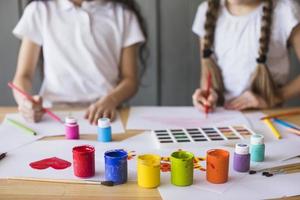 colores de pintura colorida frente niña pintando mesa de papel blanco
