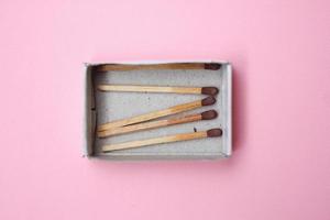 Caja de palillos de fósforos sobre fondo rosa foto