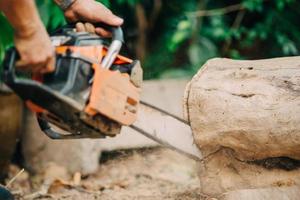 Woodman usa su motosierra para cortar el árbol. La deforestación al cortar y quemar árboles agrega más contaminación del calentamiento global a la atmósfera. foto