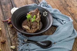 The food made of beef is in the bowl on the cloth of the wooden table photo