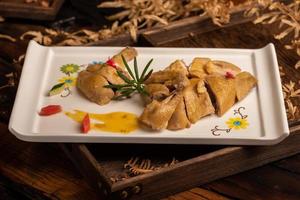 The yellow duck in the long white plate is on the wooden table photo