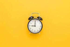 An alarm clock on a yellow background photo