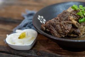 The food made of beef is in the bowl on the cloth of the wooden table photo