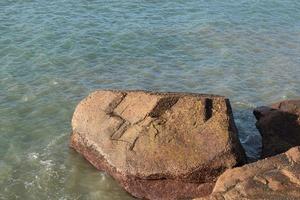 In the morning, the sun shines on the rocks and waves on the beach photo