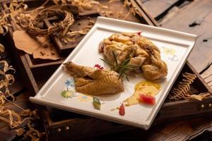 The yellow duck in the long white plate is on the wooden table photo