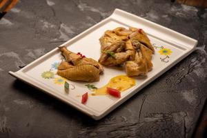 The yellow duck in the long white plate is on the wooden table photo