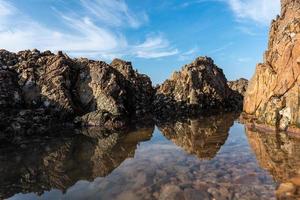The sea water between the seaside reefs reflects the Yellow reefs and the blue sky photo