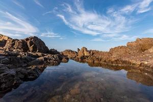 The sea water between the seaside reefs reflects the Yellow reefs and the blue sky photo