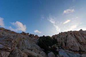 In the morning, the sun shines on the rocks and waves on the beach photo