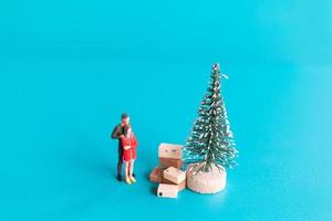 Gente en miniatura, pareja de enamorados de pie junto a un árbol de navidad foto