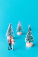 Gente en miniatura, pareja de enamorados de pie junto a un árbol de navidad foto