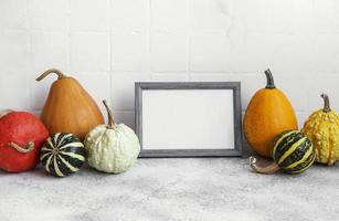 Picture frame and pumpkin decor on the table over white tile background. photo