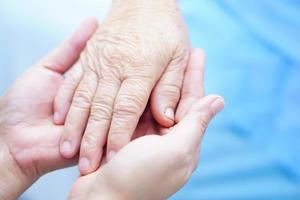 holding touching hands Asian senior or elderly old lady woman patient with love, care, helping, encourage and empathy at nursing hospital ward, healthy strong medical concept photo