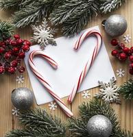 Fondo de madera navideña, tarjeta con decoración navideña, bastones de caramelo navideño, bolas navideñas y rama de abeto,