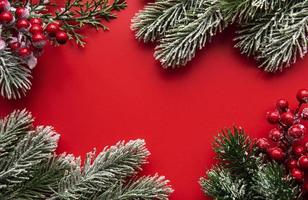 adornos navideños rojos, ramas de abeto sobre fondo rojo foto