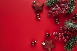 adornos navideños rojos, ramas de abeto sobre fondo rojo foto