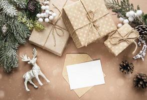 composición navideña con tarjeta, ciervos, cajas de regalo y ramas de abeto. foto