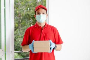 A delivery man wearing a red dress holds a parcel box. photo