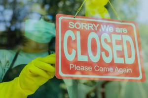 The shop owner hangs a sign to close the business in front of the door. photo