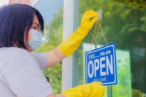 The owner of the store hangs a sign to open a business in front of the door. photo