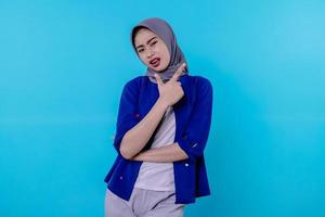 Good looking charismatic young woman with wearing hijab pointing isolated on light blue background photo