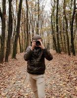 Foto de un hombre con una cámara en un bosque de otoño