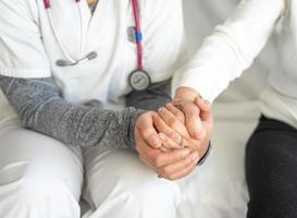 Crop doctor holding hand of patient photo