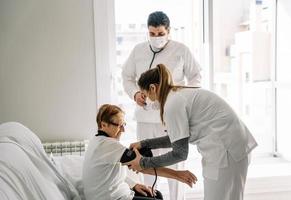 Doctors diagnosing blood pressure of senior woman