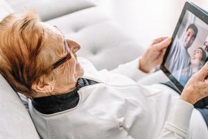 Content aged woman talking on video chat on tablet photo
