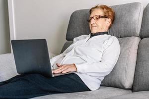 Calm senior woman browsing laptop in living room photo