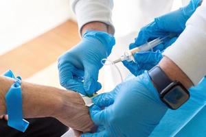 Crop medics taking blood from aged patient photo