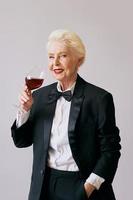 elegante mujer sommelier senior en esmoquin con copa o vino tinto. bebida, madura, concepto de estilo foto