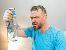 Unhappy shocked man with chronic breathing issues surprised by using  CPAP machine sitting on the bed in bedroom. Healthcare, CPAP, Obstructive sleep apnea therapy, snoring concept photo